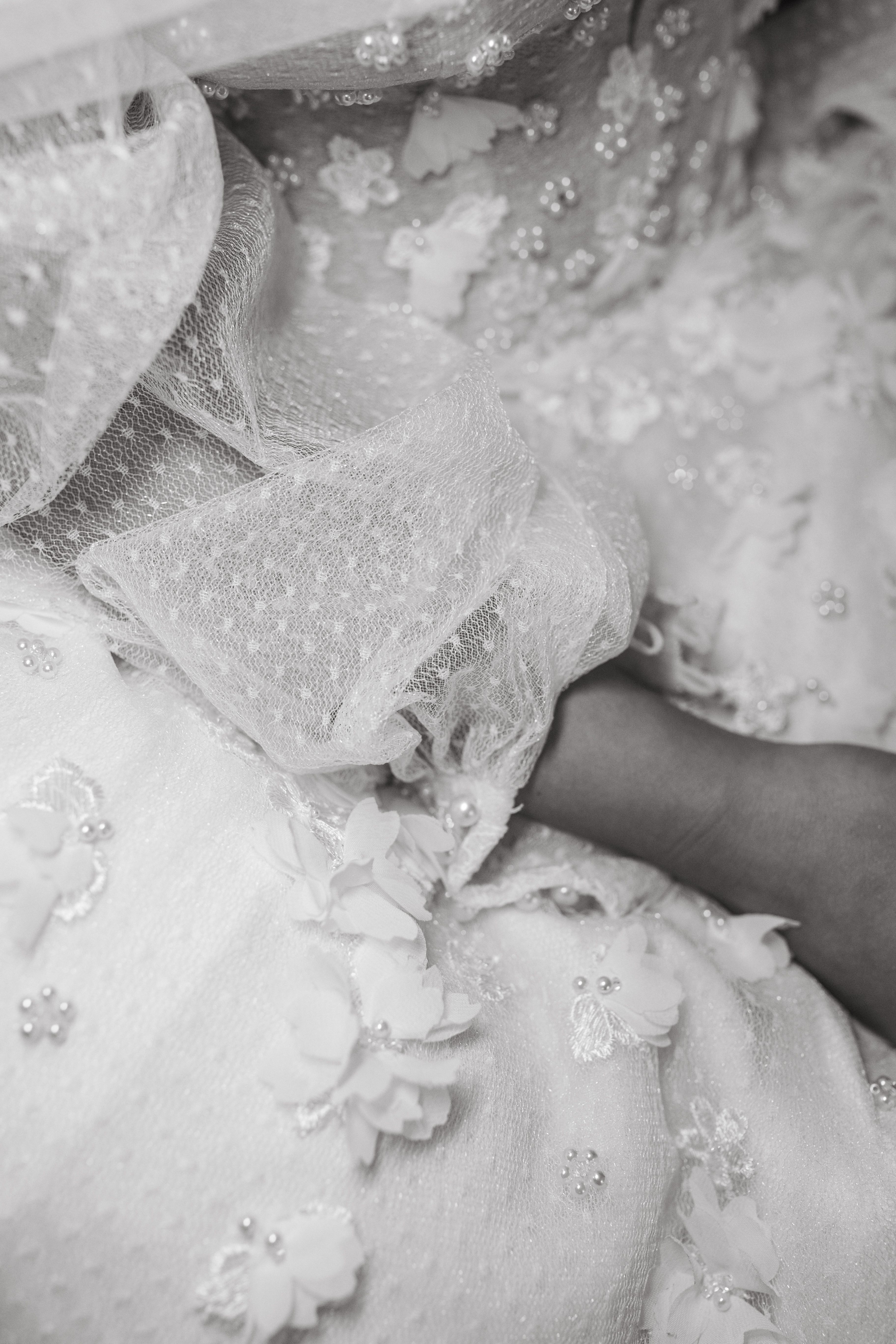 Black and white close-up of intricate wedding dress lace and embroidery.