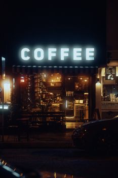 Illuminated street view of a cozy urban cafe showcasing a glowing coffee sign at night.