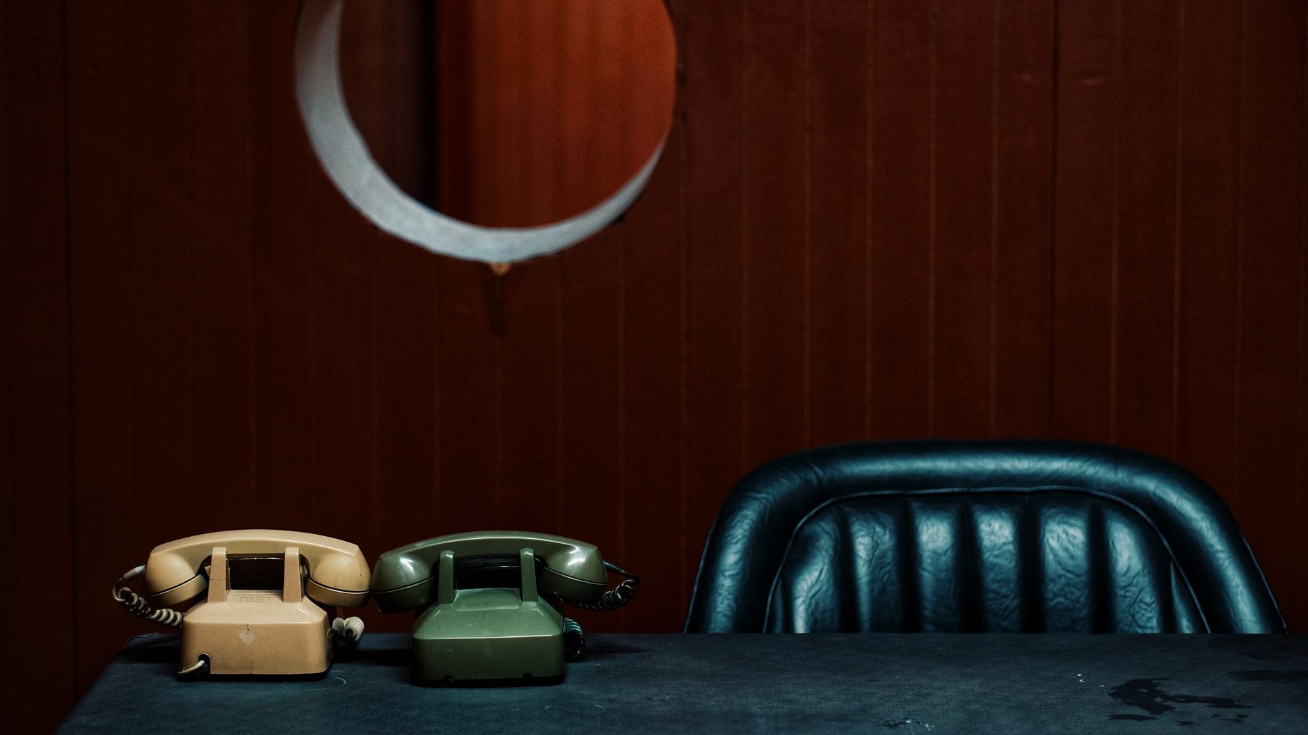 A nostalgic scene with vintage telephones and a leather chair in a classic office setting.