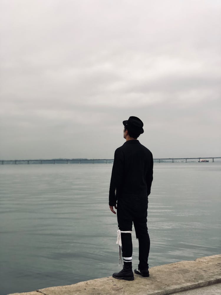 Back View Of A Man In A Suit Standing By A Body Of Water