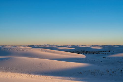 Free Breathtaking view of desert dunes at sunrise with smooth sand and clear blue sky. Stock Photo