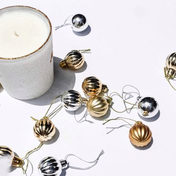 Elegant white candle with gold and silver baubles for a minimalist festive theme.