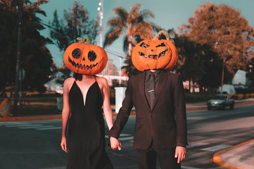 Couple Wearing Pumpkin Masks Walking on a Street