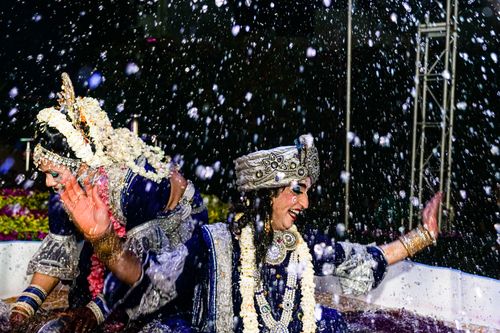 Free Smiling women in traditional Indian attire enjoy a festive dance with splashing water. Stock Photo