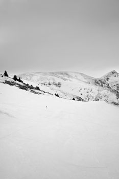 Black and white photo of a snowy mountain landscape with cloudy skies, showcasing winter's beauty.