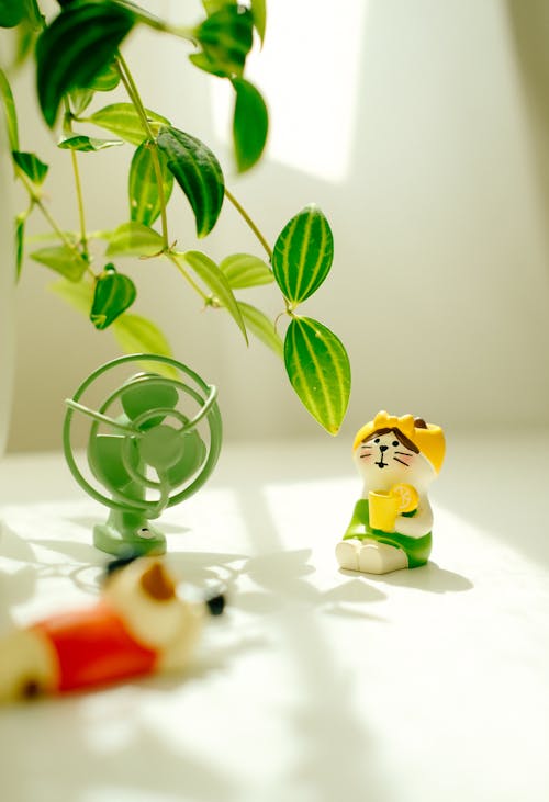 Close-up of Colorful Figurines Sitting near a Houseplant 