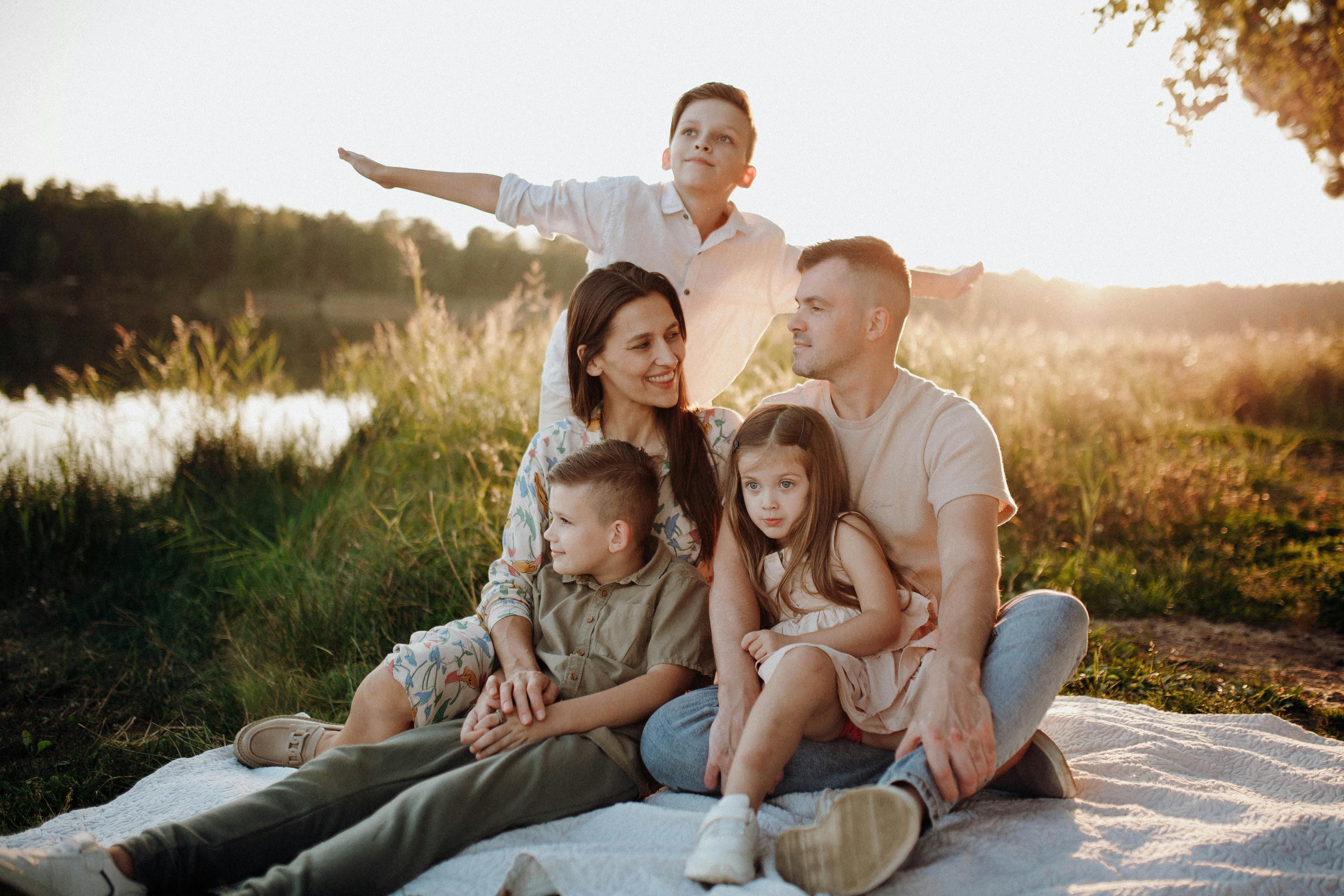 family sitting on meadow at sunset