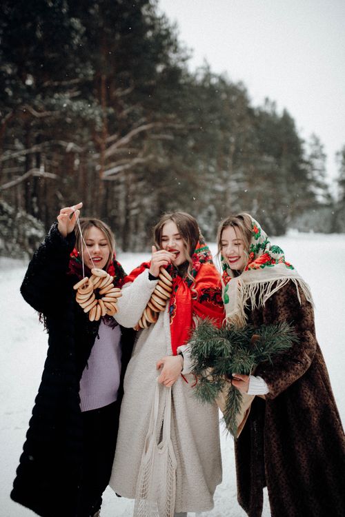 Free Three women in winter coats celebrate with pastries and pine branches, embracing the festive season. Stock Photo
