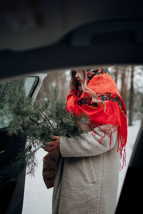 Woman in Red Floral Headscarf Holding Pine Branch