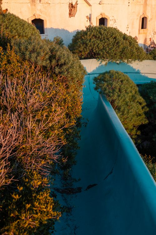 Free A scenic view of a sunlit abandoned water slide surrounded by autumn foliage in Kaş, Türkiye. Stock Photo