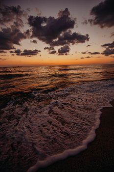 Captivating view of a beach sunset with waves and dramatic clouds, perfect for serene moments.