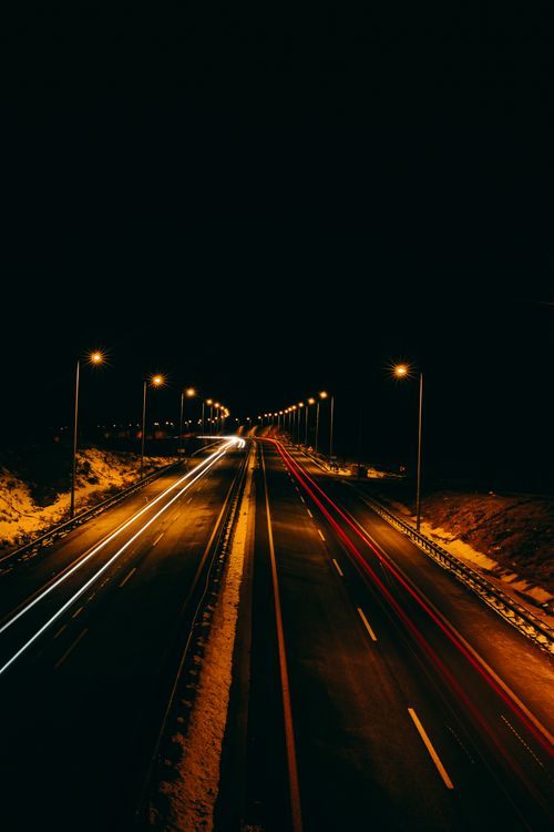Free A stunning long exposure photograph capturing a deserted highway illuminated by streetlights at night. Stock Photo