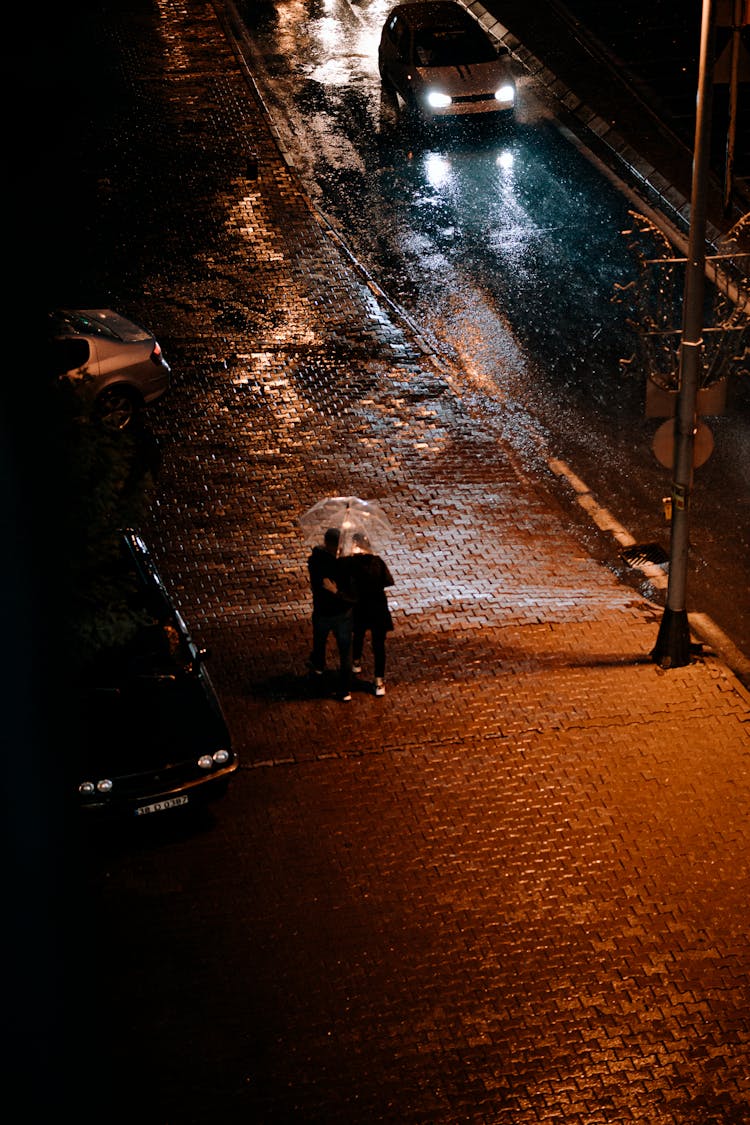 Passersby Hiding Under An Umbrella On A Cold Rainy Night