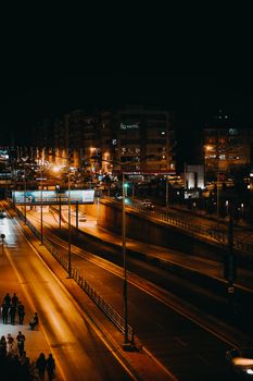 Aerial view of a well-lit city street at night with an empty road, creating a dramatic urban scene.