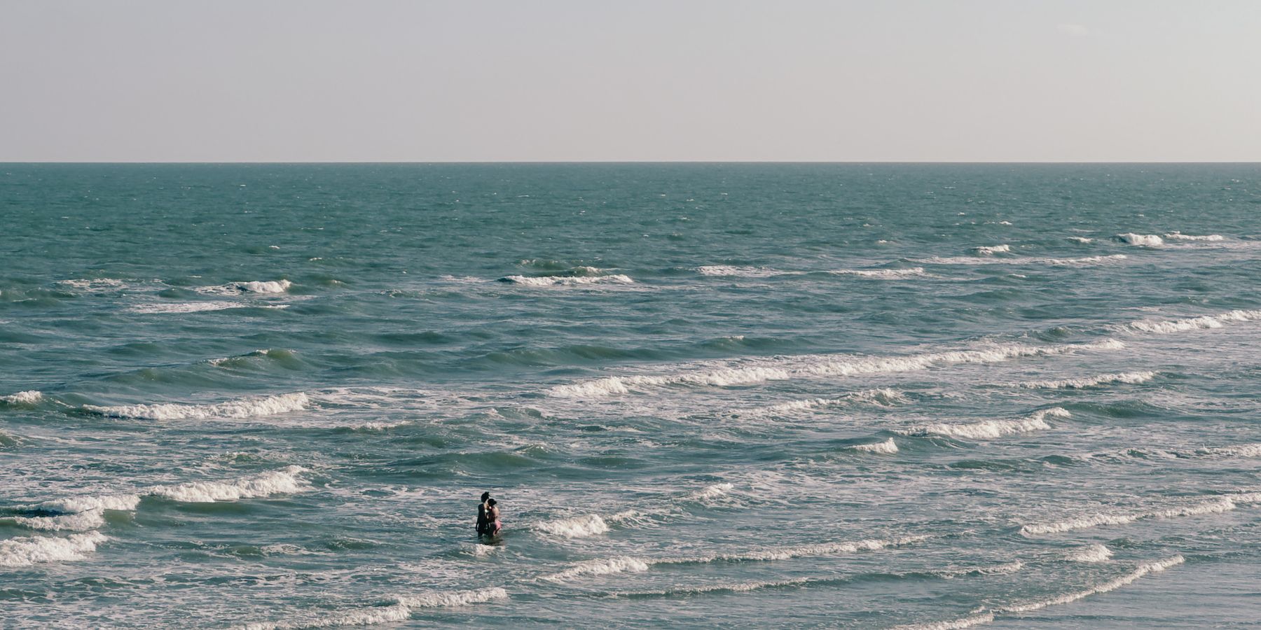 A picturesque scene of a couple enjoying the waves at Galveston beach, Texas.