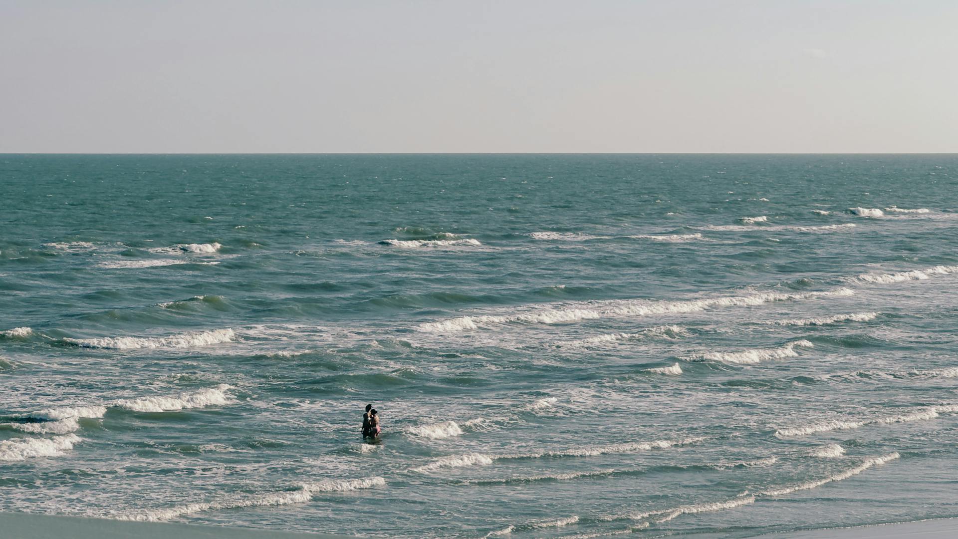 A picturesque scene of a couple enjoying the waves at Galveston beach, Texas.