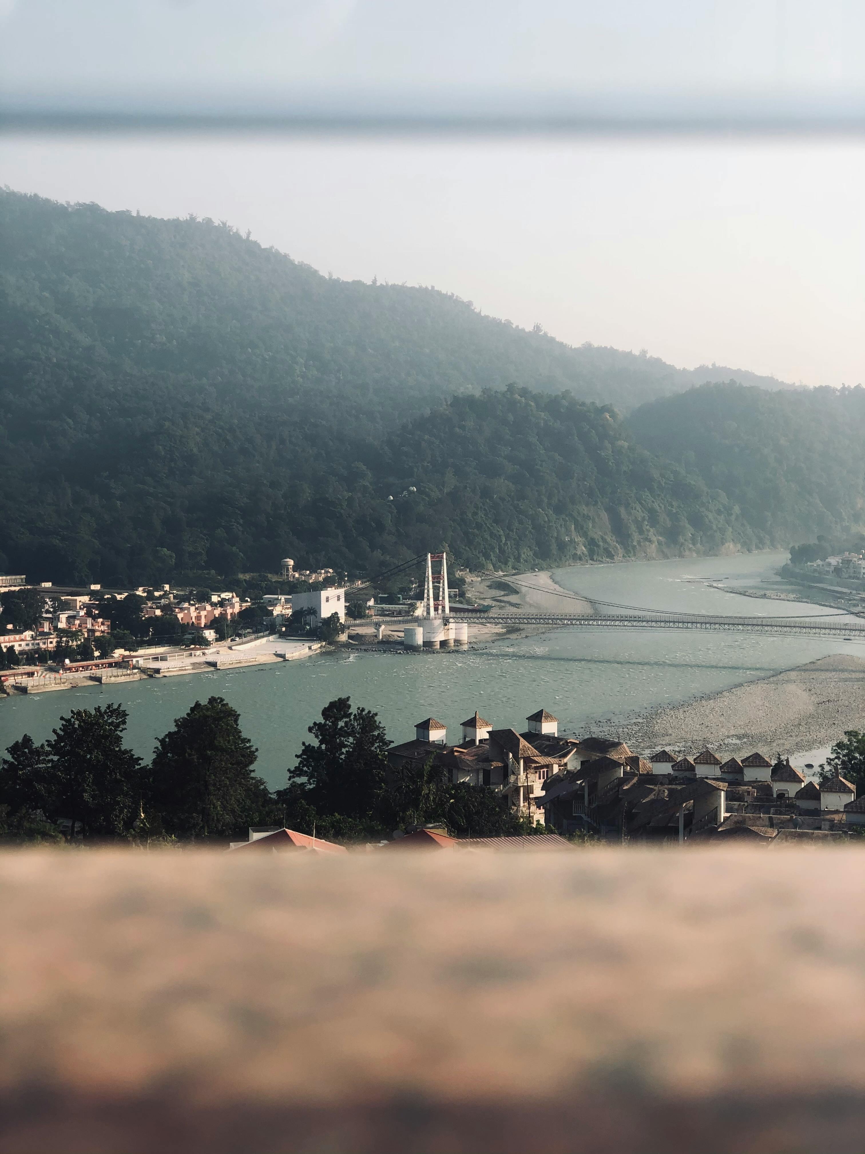 A tranquil view of Rishikesh with the Ganges River and mountains in the background, capturing the peaceful essence of this town.