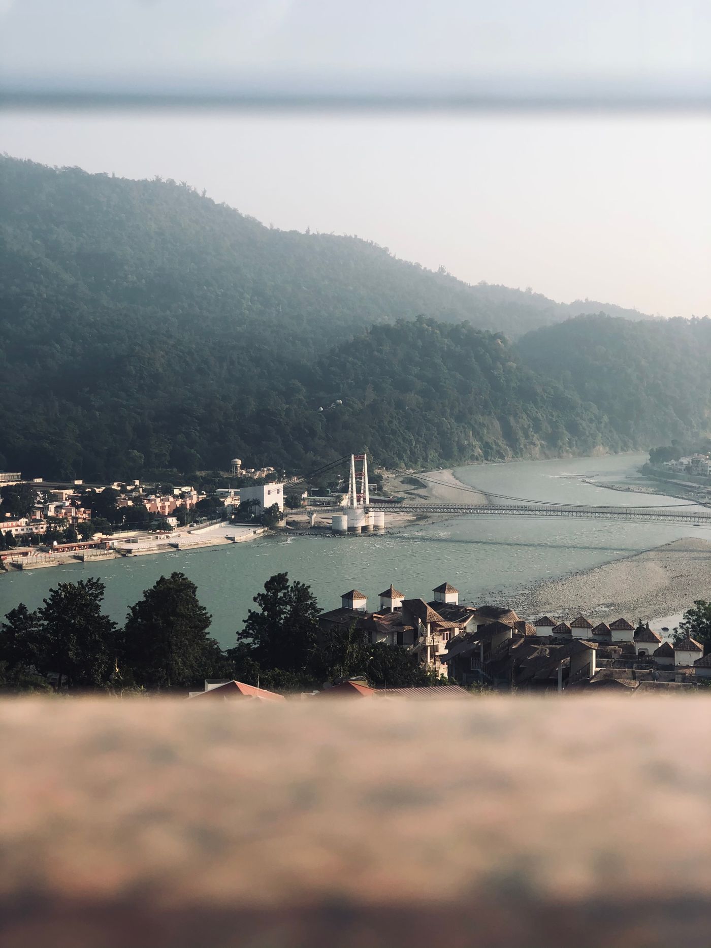 The town of Rishikesh beside the Ganges with forested Himalayan foothills rising behind it.