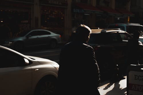 Man in Jacket Walking by Cars on Street