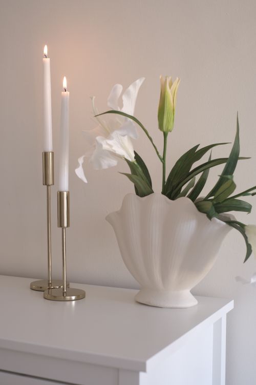Free A sophisticated interior setup featuring a floral arrangement and lit candles on a white surface. Stock Photo