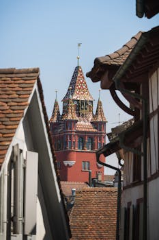 Captivating view of Basel's iconic red tower framed by traditional houses, showcasing Swiss architecture.