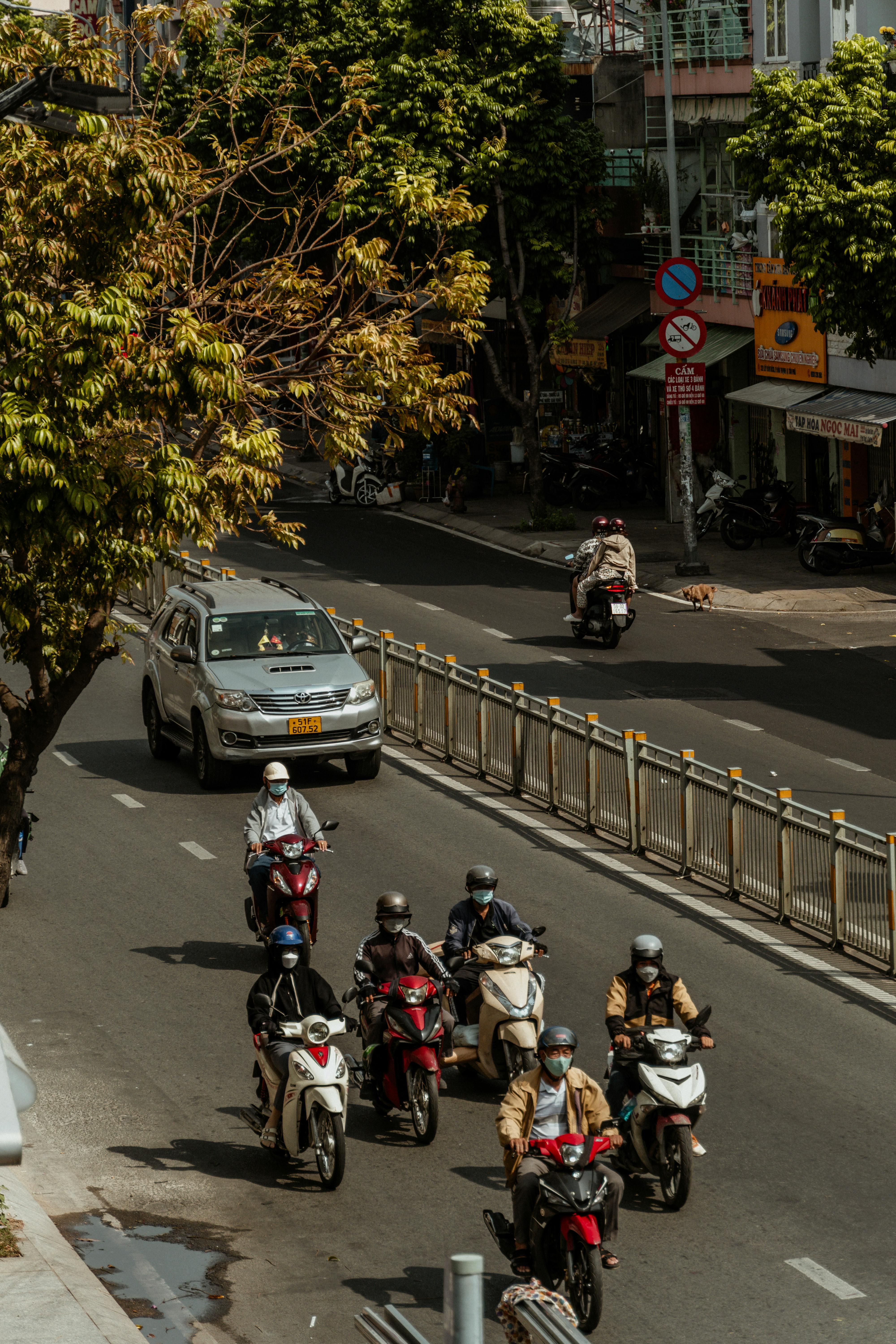 Street view showcasing multiple motorbikes and a car in an urban cityscape. Daytime shot.