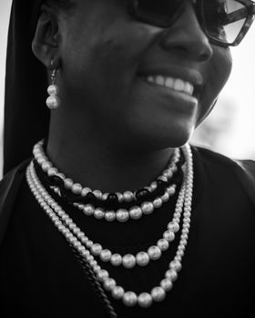 Elegant black and white close-up of a woman wearing layered pearl necklaces and earrings.