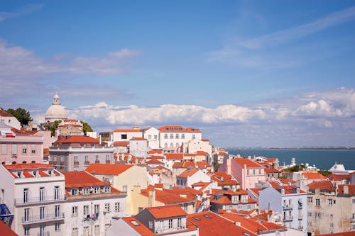 Free Charming Lisbon cityscape with red rooftops and Tagus River under a clear blue sky. Stock Photo