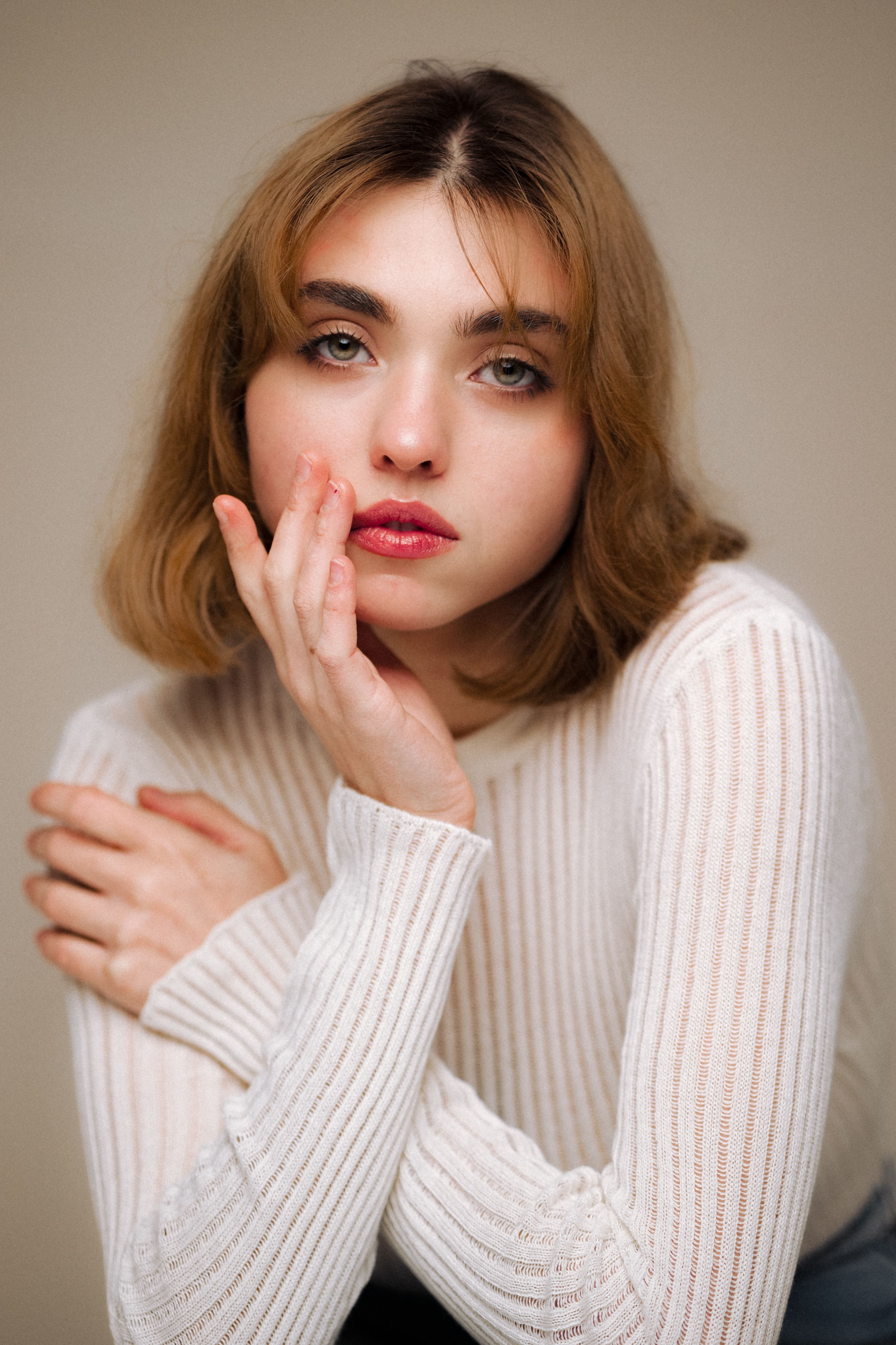 Woman wearing a neutral knit sweater against a plain studio backdrop