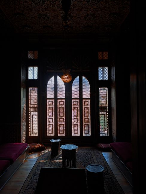 Beautifully decorated historic room interior with intricate window design and moody lighting.
