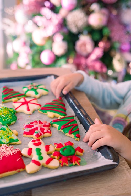 Hands of a Child Touching a Tray of Christmas Cookies