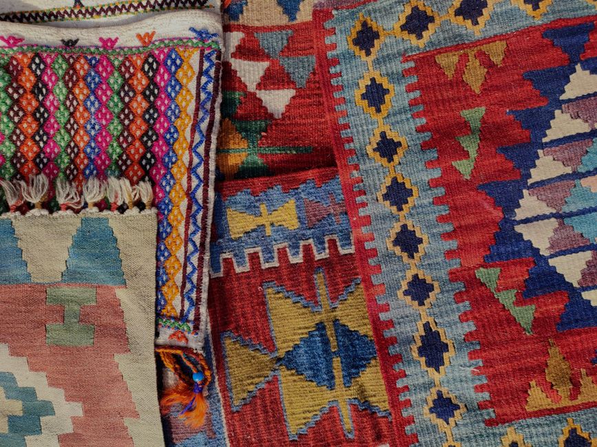 Close-up of vibrant handmade rugs with geometric patterns in a warm retro style.