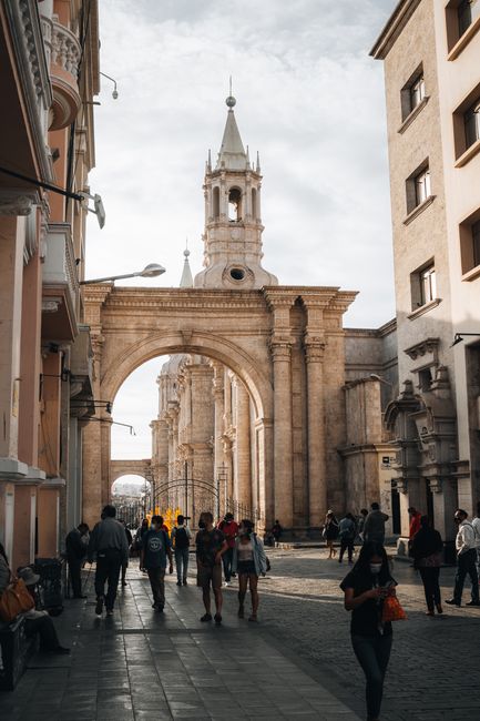 A vibrant street scene with people walking near the Basilica Cathedral in Arequipa, Peru.