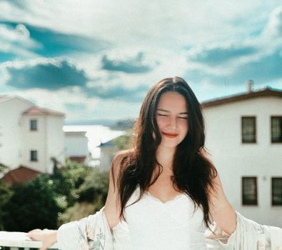 Close-up portrait of a woman smiling with eyes closed, basking in the sunlight outdoors.