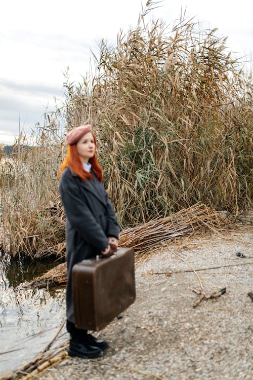 Woman Holding Suitcase by the Lake 