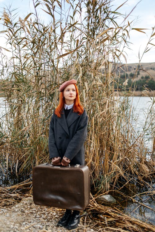 Woman Holding Suitcase by the Lake