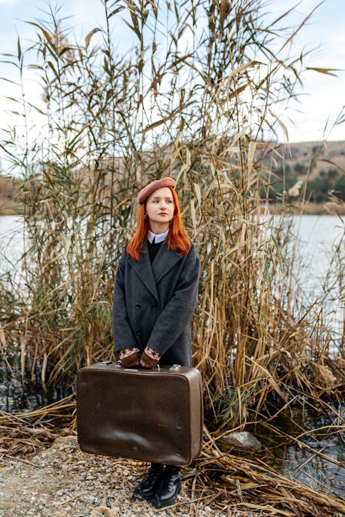 Woman Holding Suitcase by the Lake 