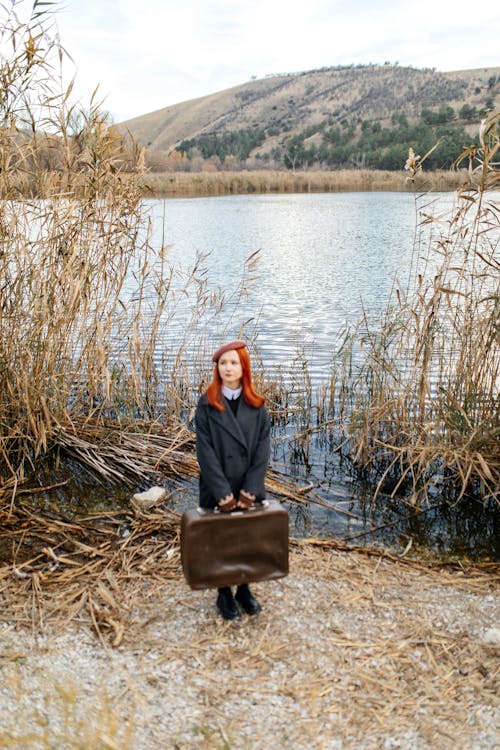 Woman Holding a Suitcase by the Lake 