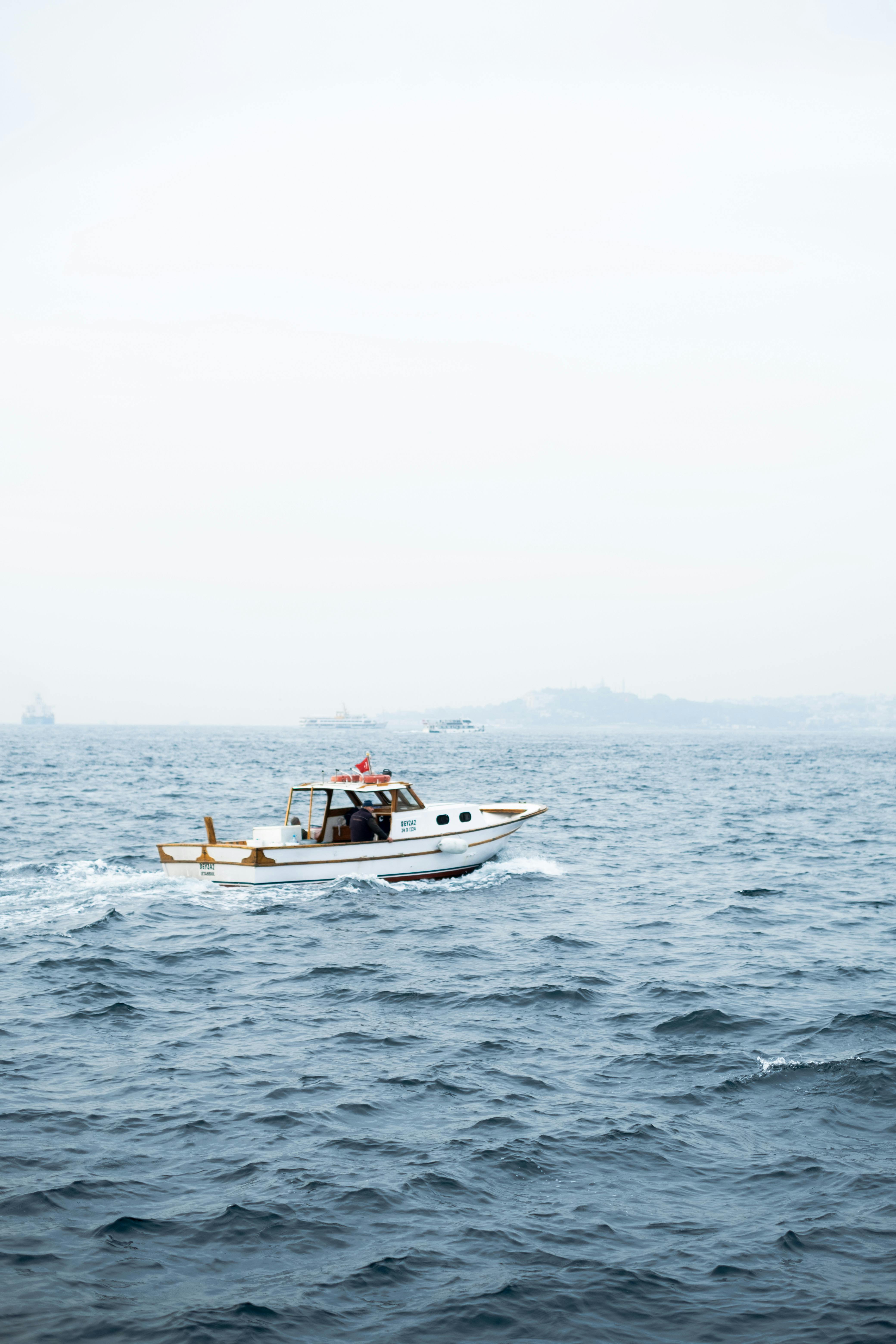 A motorboat cruising through foggy waters in Istanbul, Türkiye with a visible skyline.