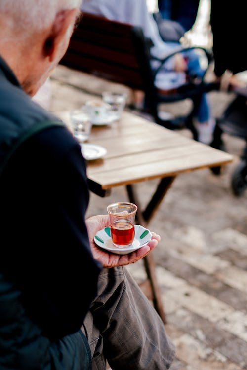 Man Sitting and Holding Glass of Turkish Tea on Plate