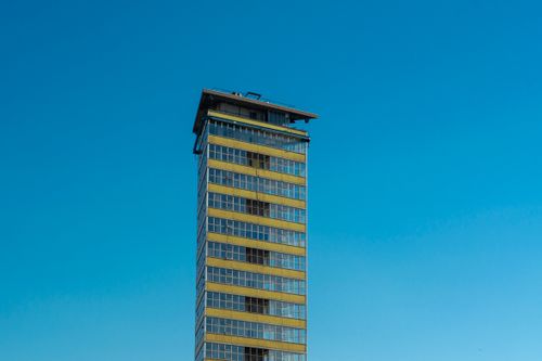 Free Tall modern skyscraper in Den Haag with glass facade under a clear blue sky. Stock Photo