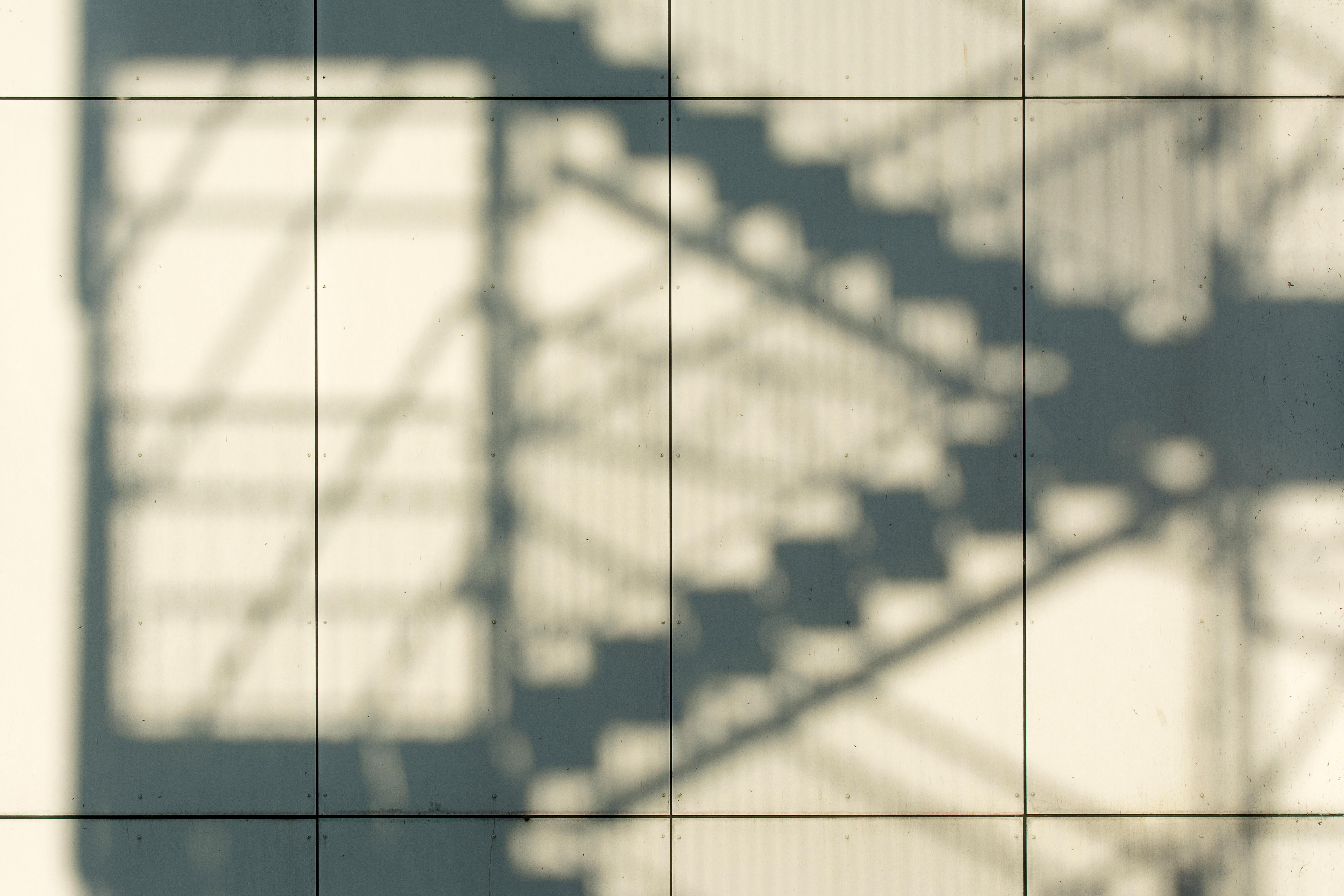 Shadow of staircase on modern building wall, creating abstract patterns.