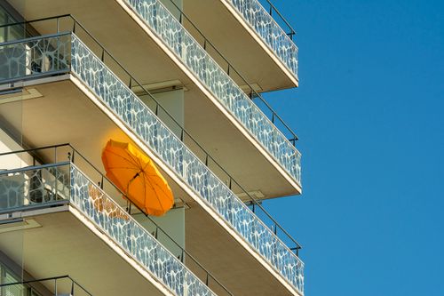 Free Vibrant urban living captured with a striking orange umbrella on a contemporary balcony. Stock Photo