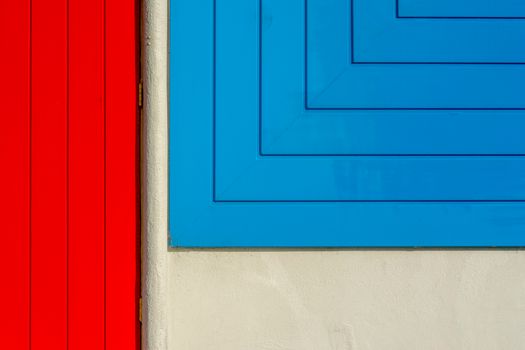 A striking abstract image featuring geometric patterns in red and blue on a building wall.