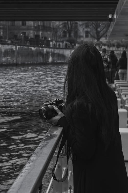 Woman Standing with Camera by Railing in Black and White