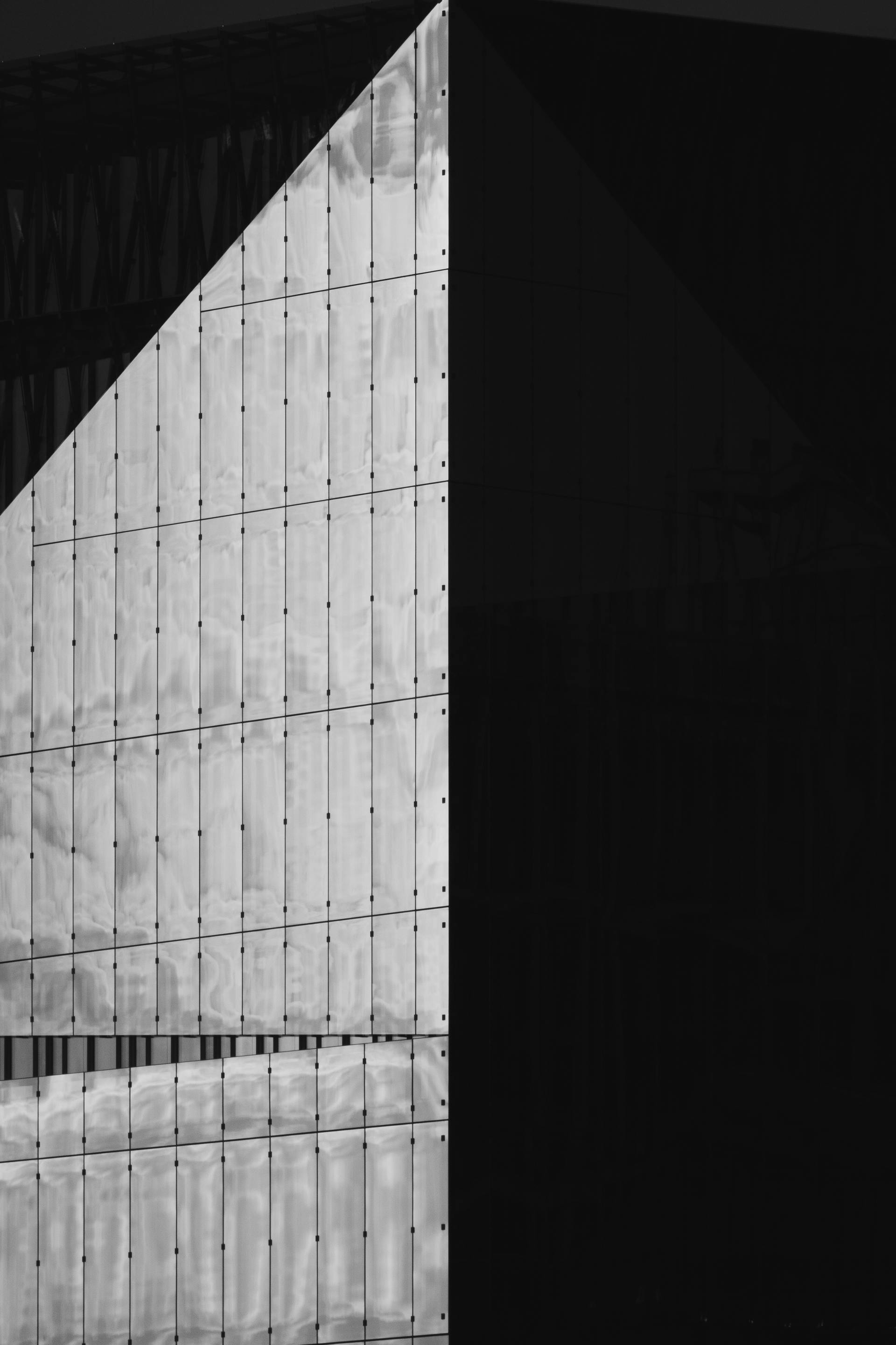 Dramatic grayscale image of a modern glass building with geometric design elements.
