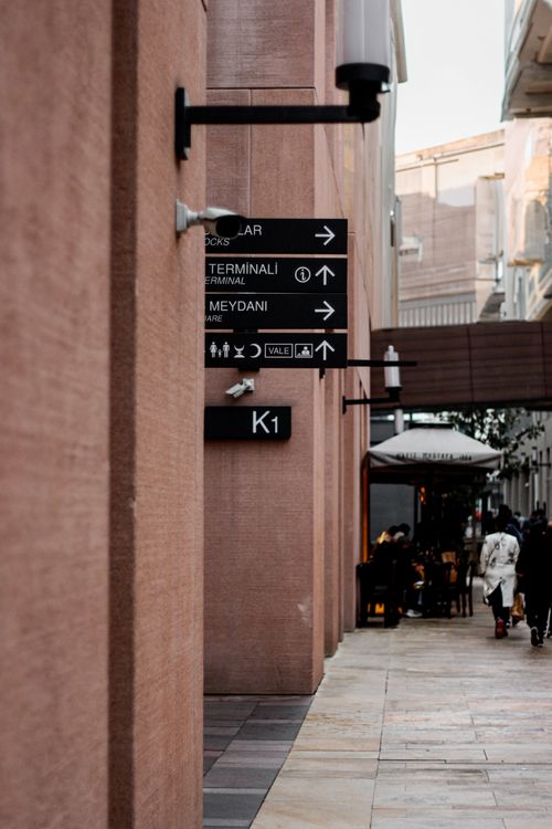 Free City sidewalk with directional signs and people walking, capturing a busy urban atmosphere. Stock Photo