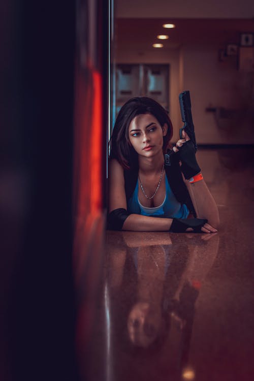 Young Woman in a Costume Lying on the Floor with a Fake Gun 
