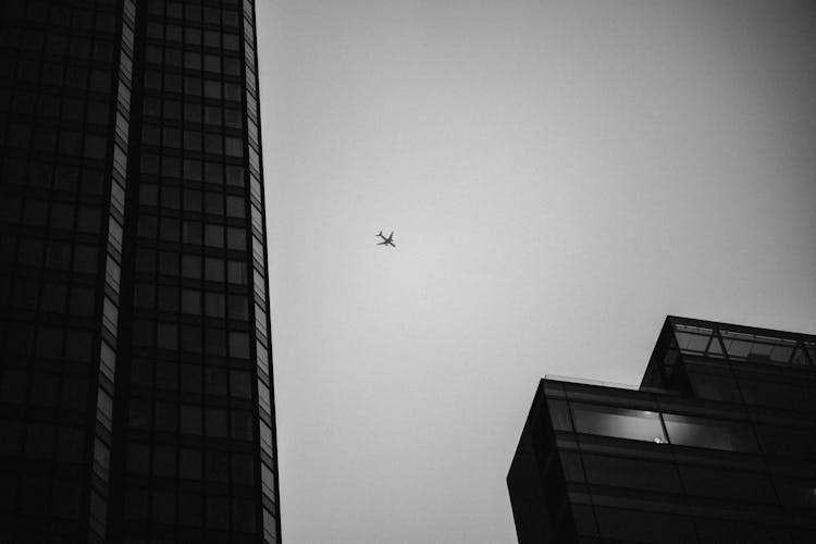 Plane Flying Above City In Black And White 