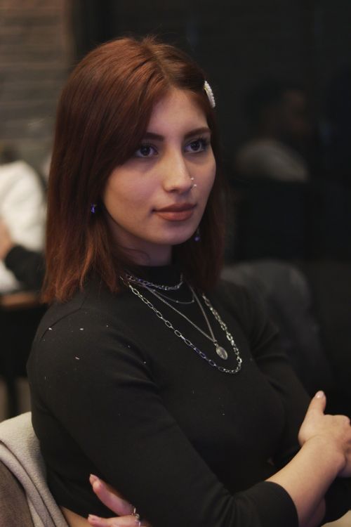 Free Portrait of a stylish woman with brown hair wearing black top and necklaces indoors. Stock Photo